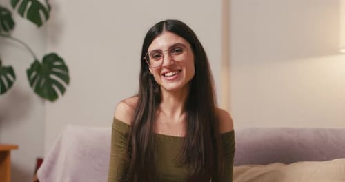 Mulher morena acena com a mão expressando calorosa saudação ao interlocutor