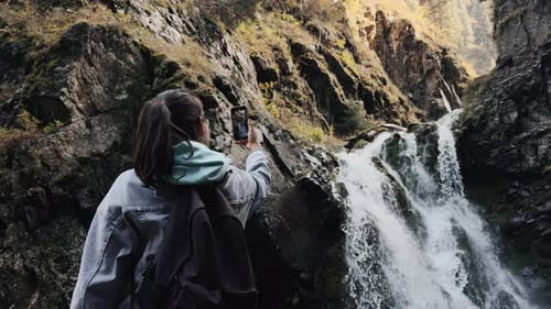 Young Female Tourist Making a Video of the Waterfall on Her Smartphone Back View Woman Filming a