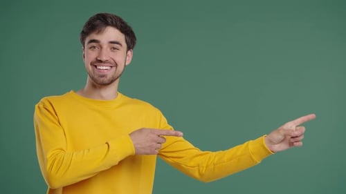 Young Smiling Man Presenting Something Isolated On Green Background Portrait