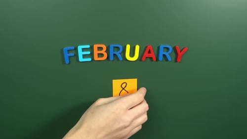 Hand sticking a sticker 8 February calendar day on school board. 8 date of February. Eighth day