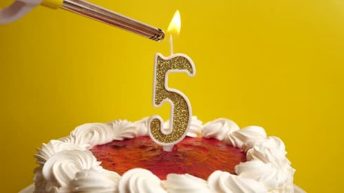 Number Five Candle on Birthday Cake Being Lit
