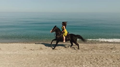 Woman Riding Black Horse on Sandy Beach