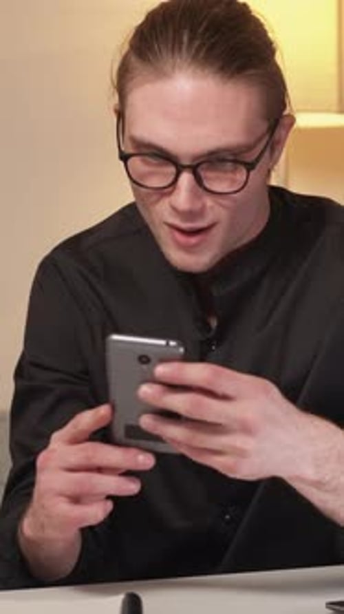 Man Celebrates Good News on Smartphone Indoors