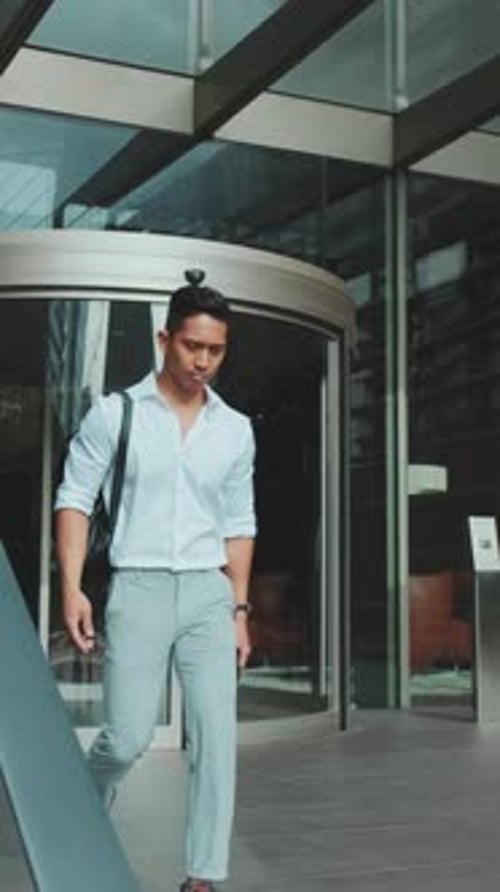 Jovem empresário saindo do centro de negócios com smartphone