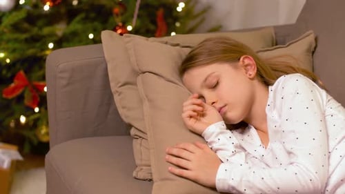 Sleeping girl on sofa with Christmas tree
