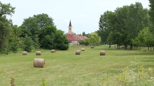 Round Hay Bales In The Countryside Near The Town. - wide shot