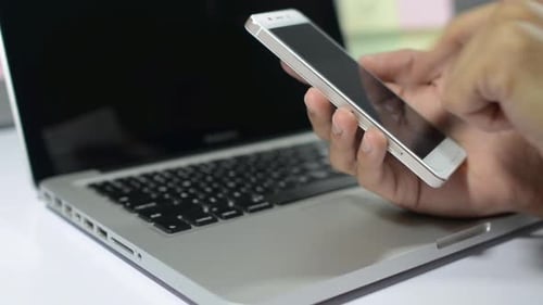 Hands Using Smart Phone Over Laptop