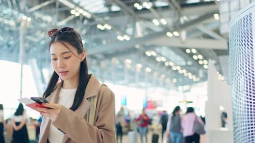 Asian young woman passenger checking departure boarding pass in airport.