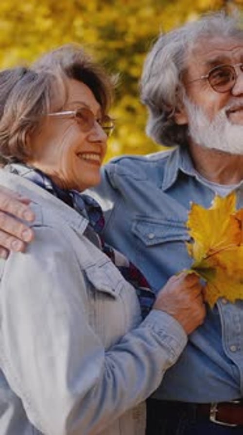 Pensioners Embracing Each Other and Talking in Autumn Park