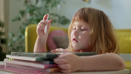 Child Drawing on Tablet at Table Indoors