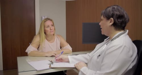 Woman Doctor Consults Patient at Desk in Office