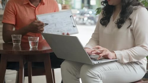 Colleagues Using Laptop and Working on Business Plan in Cafe