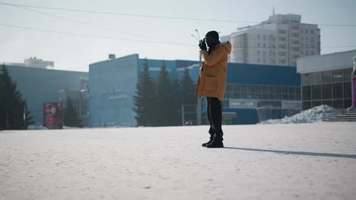 Man Taking Pictures in Snowy Urban Winter Landscape