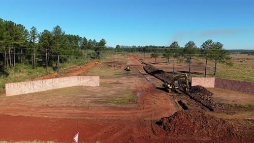 Excavators dig large trench for construction in Argentina rural red soil landscape