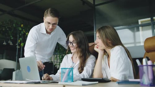 Team Meeting in a Modern Office Where a Man Addresses Two Women While They Collaborate at Their Desk