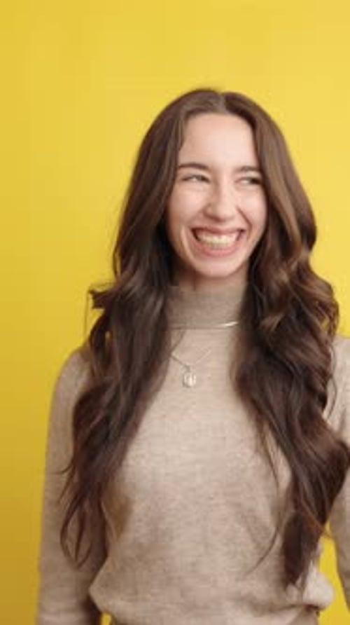 Cheerful Woman Smiling on Yellow Background in Studio Setting