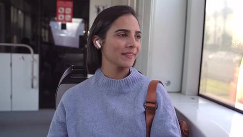 Young woman enjoying music with wireless earphones while riding public transport