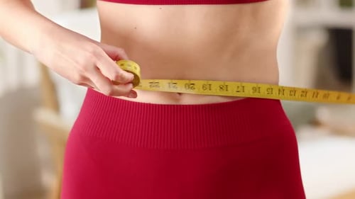 Woman Measures Waist with Tape Indoors