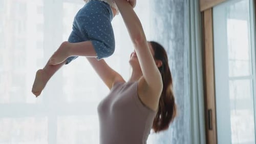 Loving Mother Playing With Her Baby in Bedroom