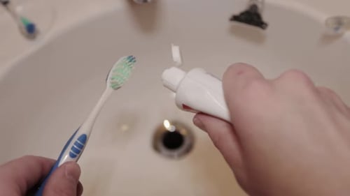 Toothpaste is layered onto a toothbrush.