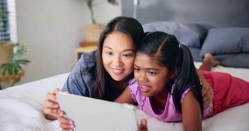 Woman and Child Using Tablet on Bed Together