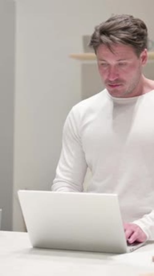 Hombre trabajando en el ordenador portátil en la cocina, vídeo vertical