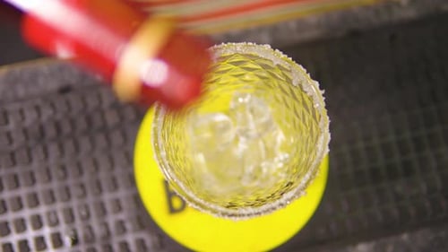Gießen Sie roten Sirup in ein am Boden mit Eis gefülltes Glas, um den Cocktail in einer Bar in Zeitlupe zuzubereiten