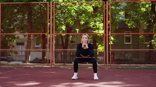 Athletic Woman Doing Squats With Resistance Band