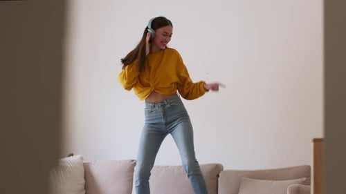 Woman Dancing Energetically on Sofa with Headphones