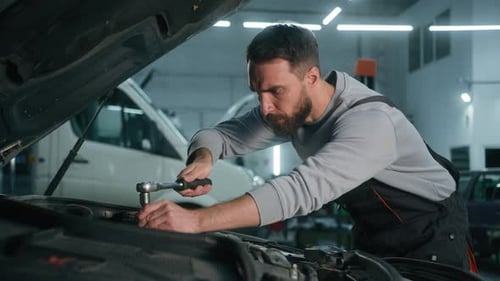 Un homme caucasien fatigué et épuisé mécanicien automobile surchargé de travail réparateur à l'intérieur d'un capot de voiture ouvert