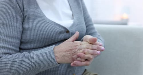 Senior Woman Massaging and Stretching Hands Indoors