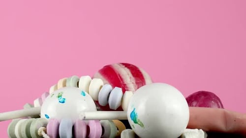 Isolated against a bright pink backdrop, a portion of tasty children's candy rotates slowly on a pla