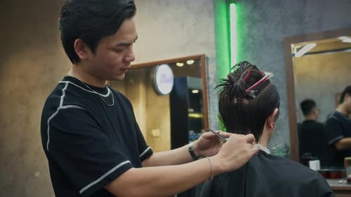Young Barber Making New Hairdo to Client at Barbershop