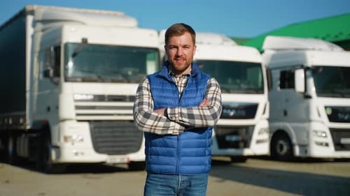 Confident Man Standing in Front of Commercial Trucks