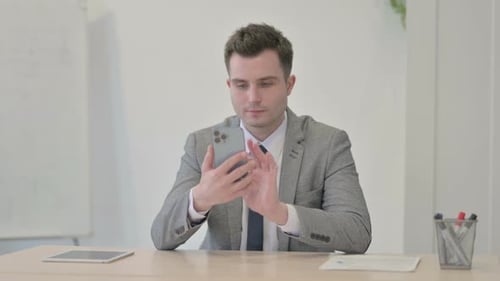 Young Businessman Browsing Internet on Smartphone in Office