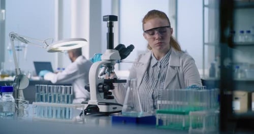 Scientist Works with Microscope in Bright Modern Lab