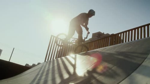 BMX Athlete Practicing Trick on Ramp in Skatepark on Sunny Day