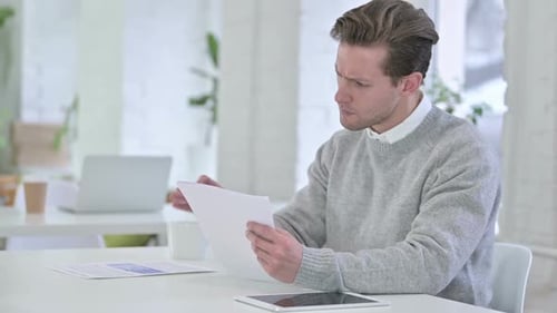 Excited Man Reads Documents in Bright Office