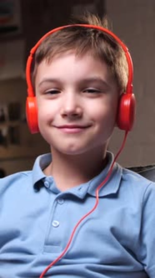 Boy Smiles Listening to Music on Headphones Indoors