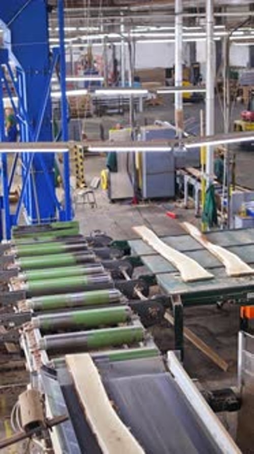 Woodworking factory indoors. Workers control the process of making boards by automated equipment