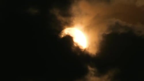 Telephoto view of the sun with dramatic dark storm clouds, horror feeling
