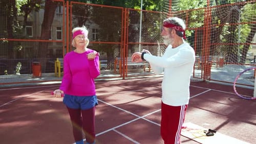 Athletic senior couple exercises together outdoors in sunshine