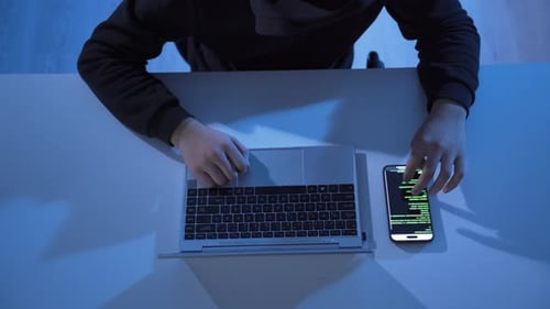 Person Using Laptop and Smartphone with Code