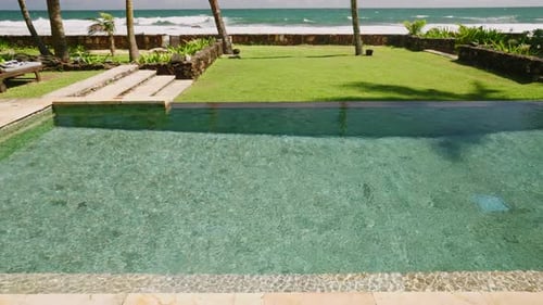 Luxurious Resort Villa with Swimming Pool and Green Lawn with Palm Trees Near Sandy Ocean Shore on