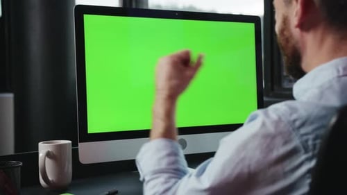 Eine Person, die fleißig an einem Computer mit einer hellgrünen Bildschirm-Hintergrundeinstellung arbeitet