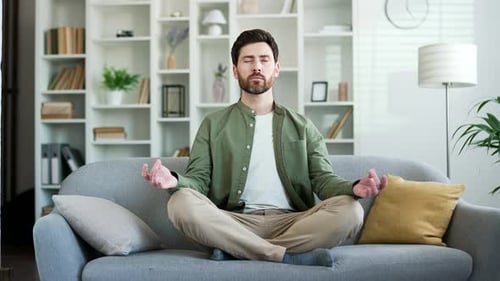 Relaxed Man Meditating on Sofa in Bright Living Room