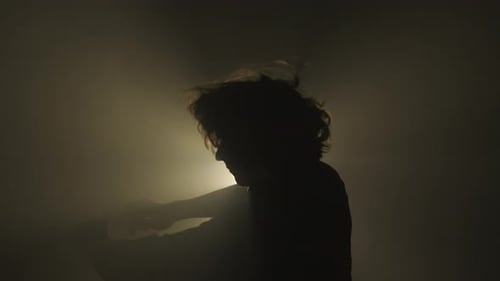 Male Model Against Bright Light on Black Background in Studio Man Clubber Silhouette Dancing