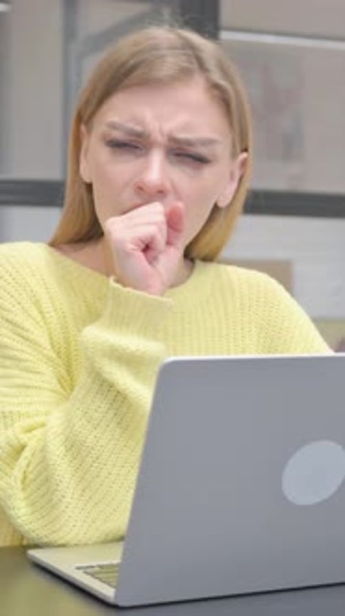 Woman Coughing While Working at a Laptop