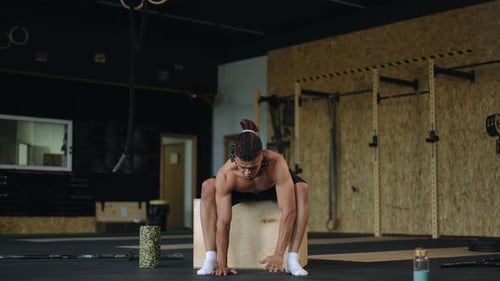 Man Stretching in Gym on Plyometric Box