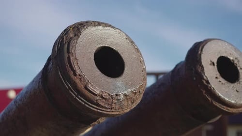 Cannon Tubes and Muzzles Covered with Rust Against Blue Sky
